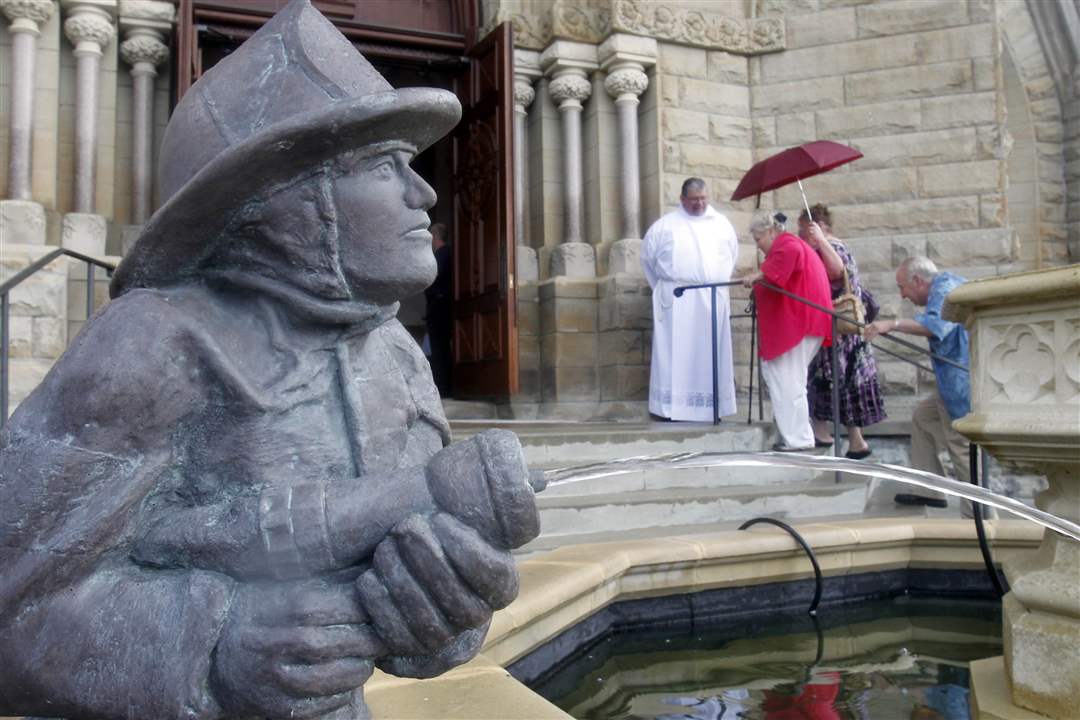 Firefighter-sclupture-with-priest-in-background