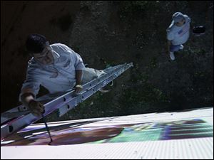 Broadway-murals-projection.jpg Alberto Marin stands on a ladder as he traces from a projection.