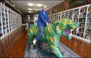 Dorinda Shelley sits atop the green-and-yellow tiger statue in her bookstore, Library House Books and Art. Her passion for books led her to open the store, and a history-themed book shop is set to open this month.