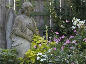 An angel looks down on a mix of petunias, impatiens and phlox.