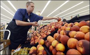 Caleb Tollefson stocks a display of nectarines and peaches at a Hy-Vee grocery store in Sioux Falls, S.D.  The Midwest drought has made corn, soybeans, and other grains much more expensive.
