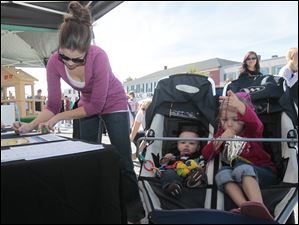 Sarah-Brossia-of-Perrysburg-left-signs.jpg Sarah Brossia, of Perrysburg, left, signs up for a chance to win a gift certificate at the Signature Harley-Davidson of Perrysburg table while her children Graham, 10 months, and Madalynn (cq), 3.5. wait. A festival brings out a crowd in downtown Perrysburg.