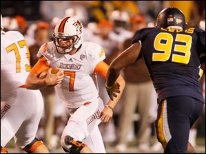 Phil-Lewis.jpg Bowling Green quarterback Matt Schilz, left, runs for a first down as Toledo defensive lineman Phil Lewis moves in during the third quarte.