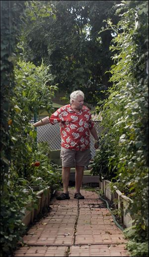 Mike Monus stands in his backyard garden that has raised-beds to accommodate his physical limitations.