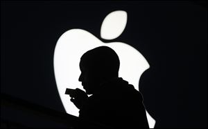 Corey Rucker of Powder Springs, Ga.  is silhouetted against the Lenox Mall Apple store icon, as he waits Friday for the release of the iPhone 5 in Atlanta.